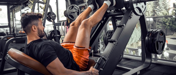 A man performing a seated leg press during his gym session.
