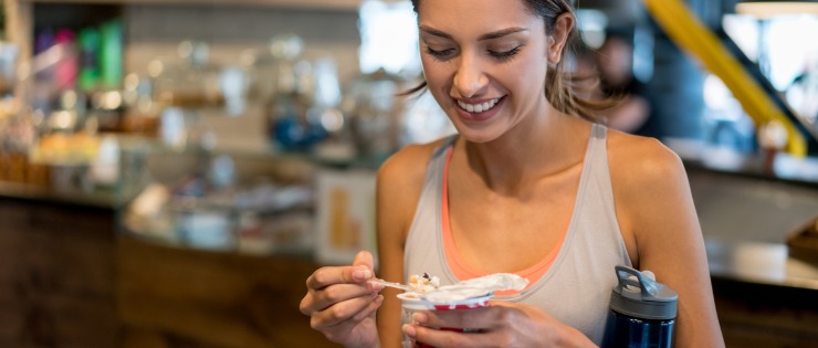 A woman eating a healthy snack after finishing her workout at the gym.