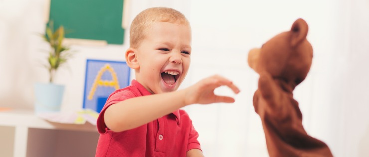 Young boy playing with a bear hand puppet to help treat autism (Asperger’s syndrome). 