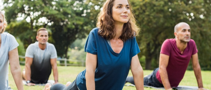 Female doing yoga outdoors with friends to increase activity level 