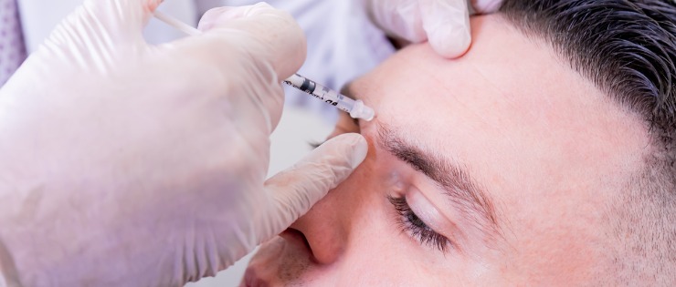 Doctor injecting botox into a male patient to treat chronic headaches