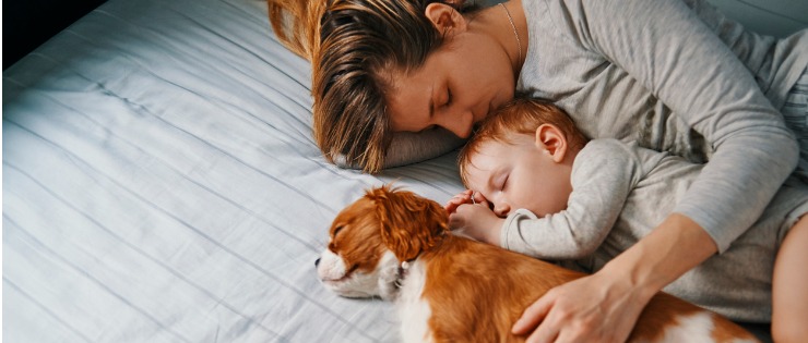 A mum and her baby co-sleeping together with their dog.