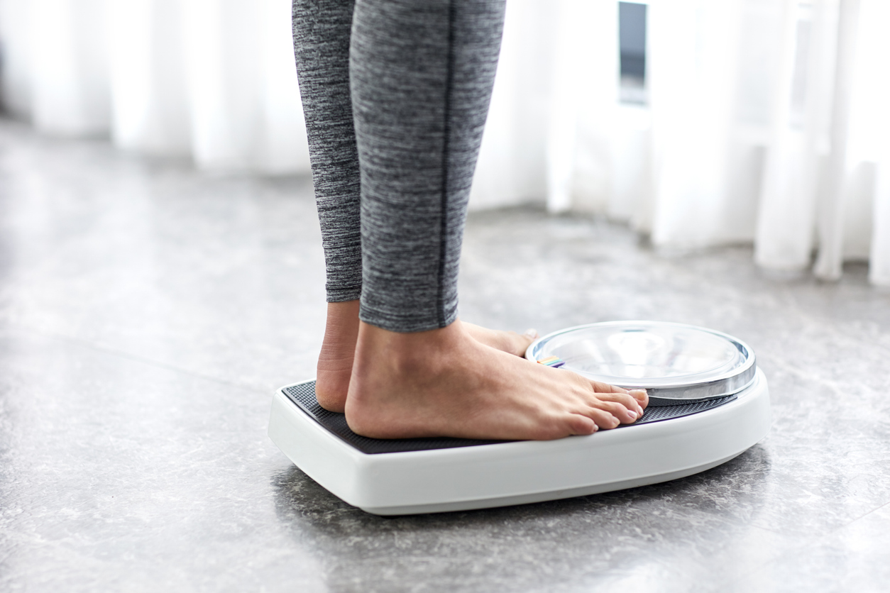 Woman checking for weight, considering what insurances cover weight loss programs