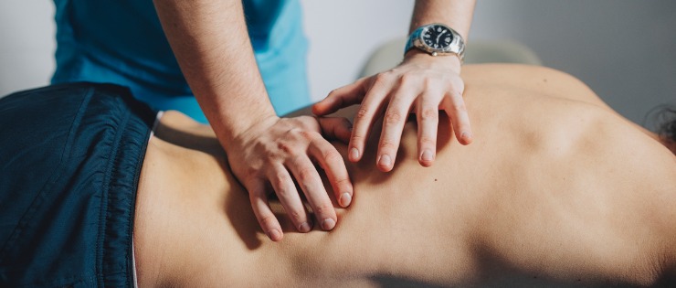 A physiotherapist conducting a massage on their client’s back to help relieve pain.