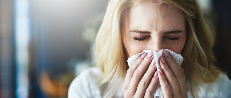 Woman sick with the flu blowing her nose. 