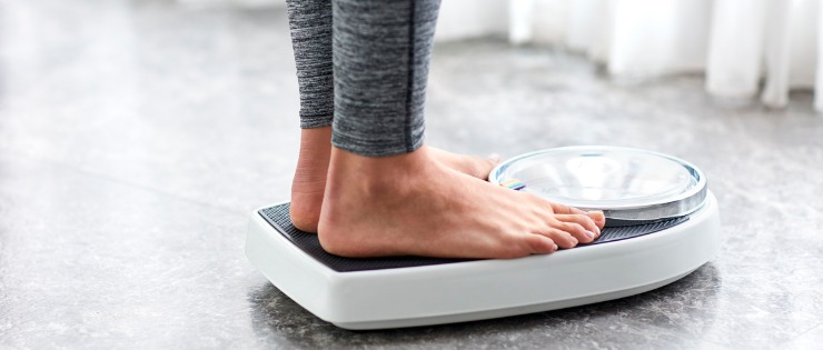 Young female standing on scales to assess if she has lost weight since drinking more green tea