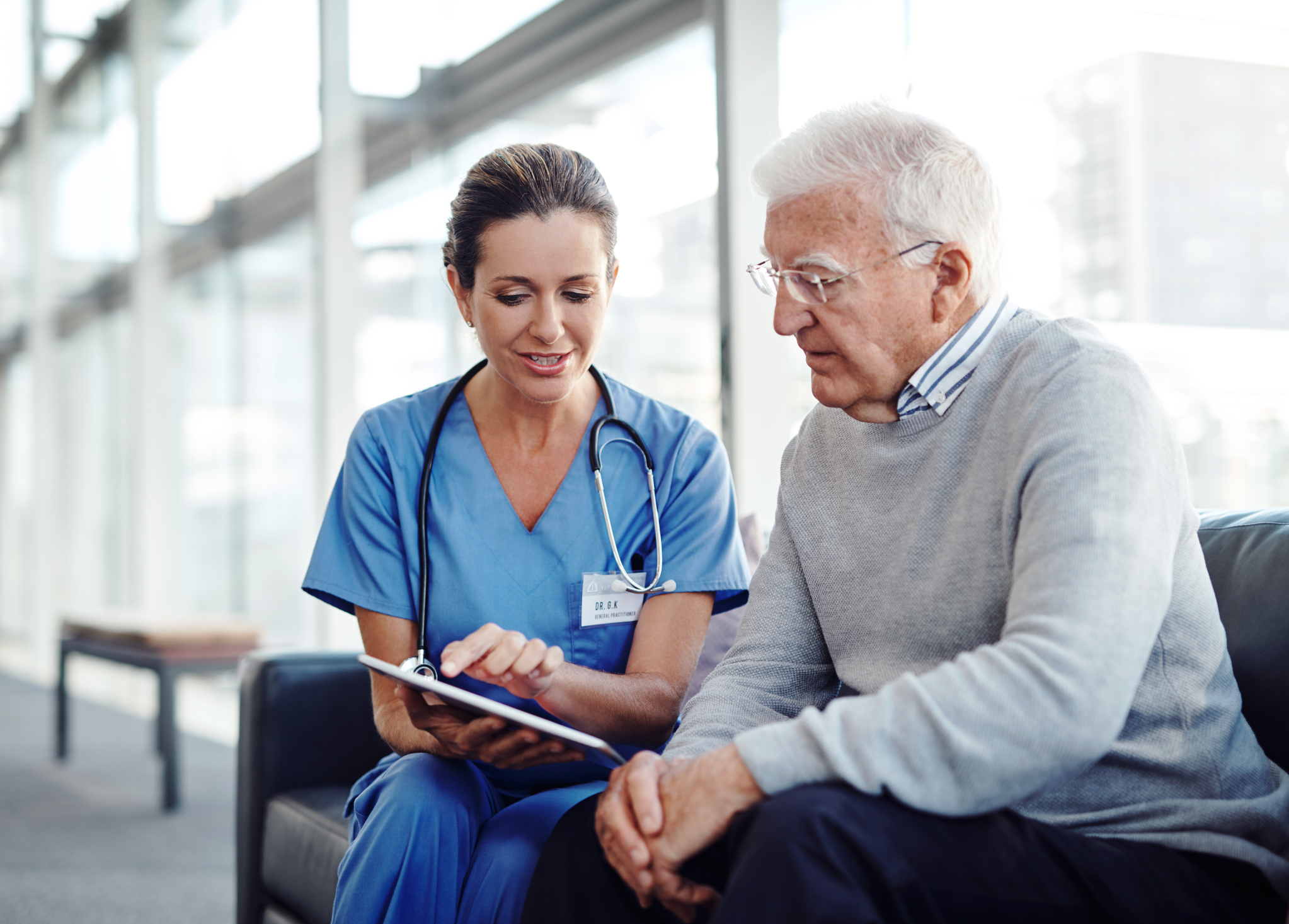 Doctor sitting on a couch chatting to a patient in a hospital