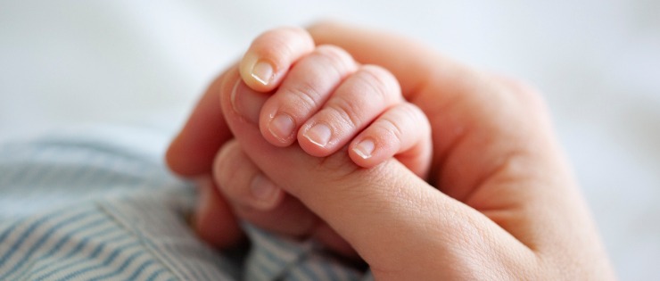 Close up of a newborn baby holding mother's hand in hospital 