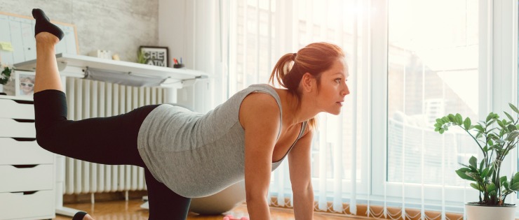 Pregnant woman doing yoga in her living room 