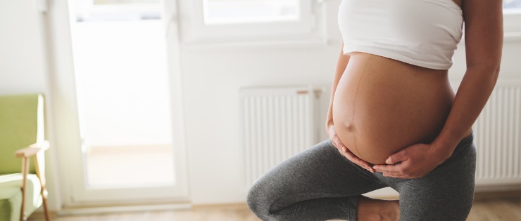 Pregnant female standing in yoga pose in her lounge room