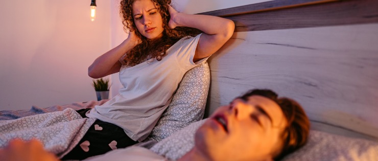 A man snoring in his sleep and disturbing his partner’s sleep.