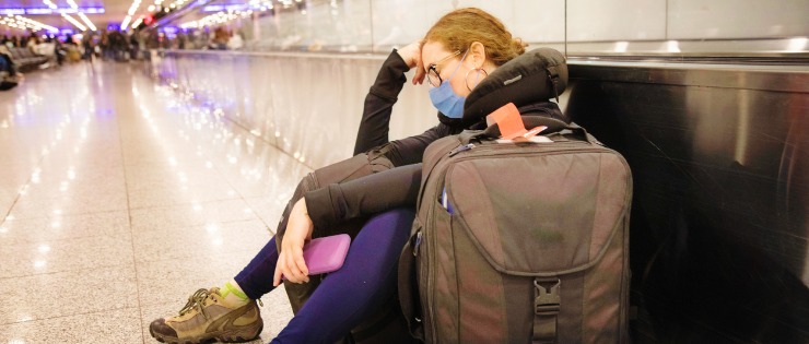Woman without travel insurance waits at the airport after her flight was cancelled due to COVID-19.