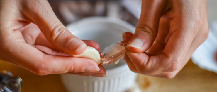 A woman peeling a clove of garlic to use as a natural remedy for hay fever.