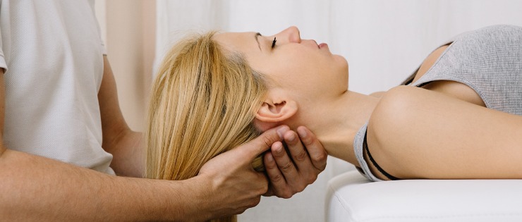 Chiropractor assessing a female patients neck pain.