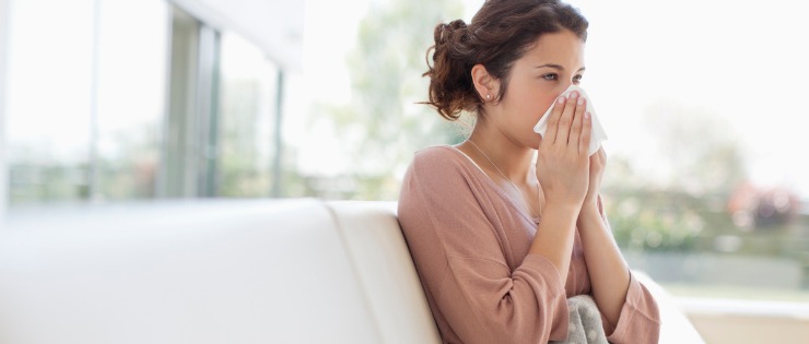 woman blowing her nose suffering from a cold
