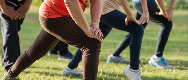 A group of people performing Tai chi in the park to help relieve symptoms of chronic pain.
