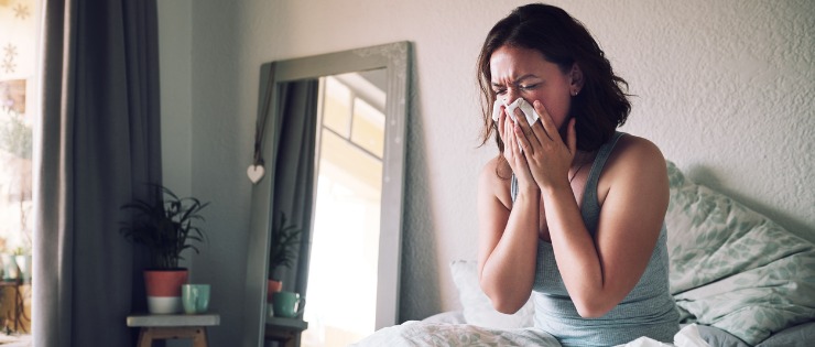 A woman is sick in bed, suffering from the flu after not receiving her vaccination.