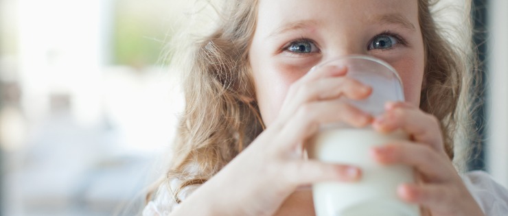 Young girl drinking a glass of dairy milk.