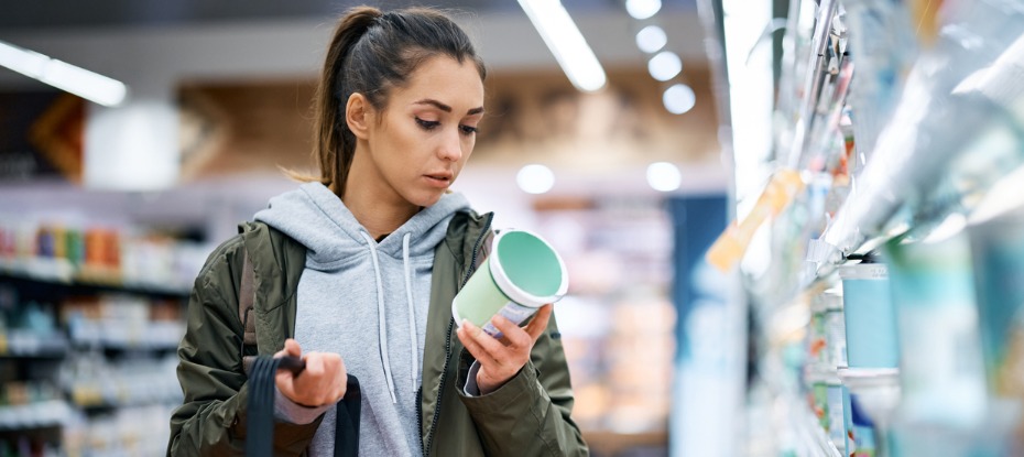 woman looking at food label behind package at the supermarket