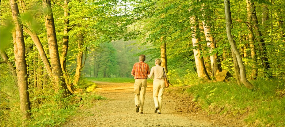 A couple enjoying a peaceful stroll in the forest, highlighting the benefits of walking for foot arthritis, arthritis foot pain, and effective foot arthritis exercises