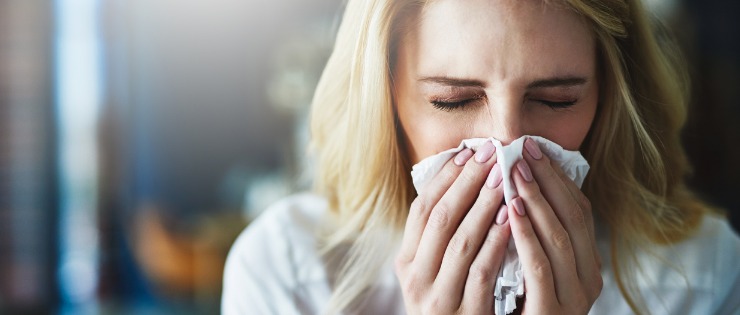 Women suffering from a cold blowing her nose