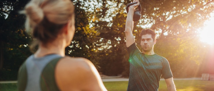 Male exercising in a park with a personal trainer 