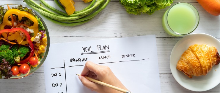 Close-up hands of a woman writing out a meal plan