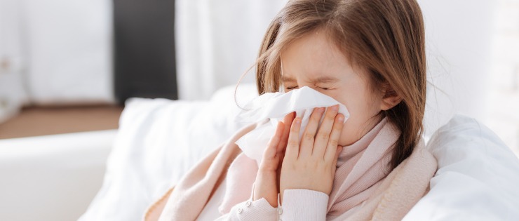 Young girl sick with the common cold blowing her nose