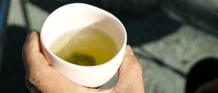 Man holding a cup of green tea to help with inflammatory bowel disease (IBD)