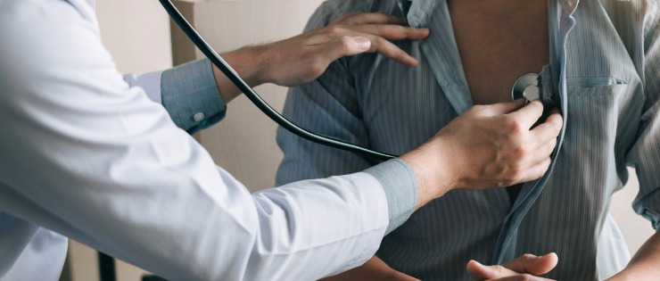 A doctor using a stethoscope to check the heart health of their patient.