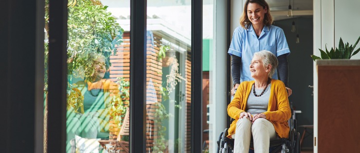 A nurse looking after an elderly lady in a wheelchair for a walk through a private hospital.