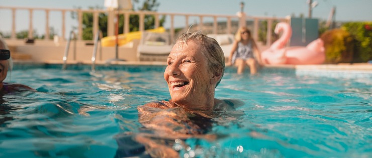 An elderly woman happily swimming because she has strong hips.
