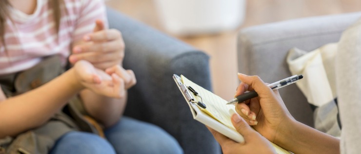 Psychologist writing down notes during mental health diagnosis with a child