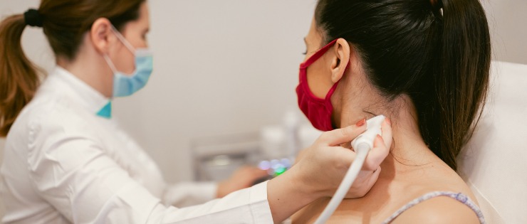 Doctor conducting an ultrasound on a woman's neck as a result of smoking.