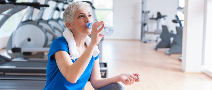 Mature aged woman drinking lots of water after a gym workout 