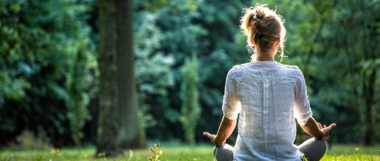 A woman in a park making time for herself and meditating