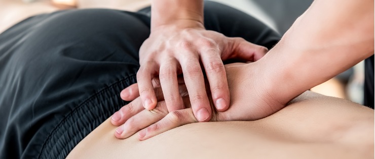 Osteopath using hands-on treatment to support the movement of the lower back