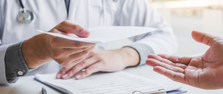 Doctor handing a document to a patient.