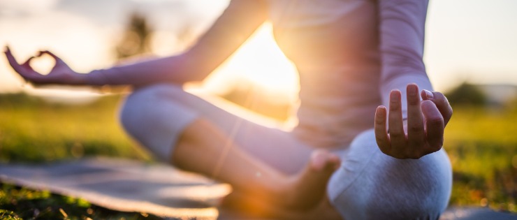 Young woman meditating in a park at sunset