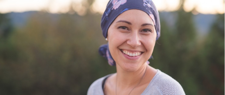 A woman with breast cancer smiling and looking at the camera.