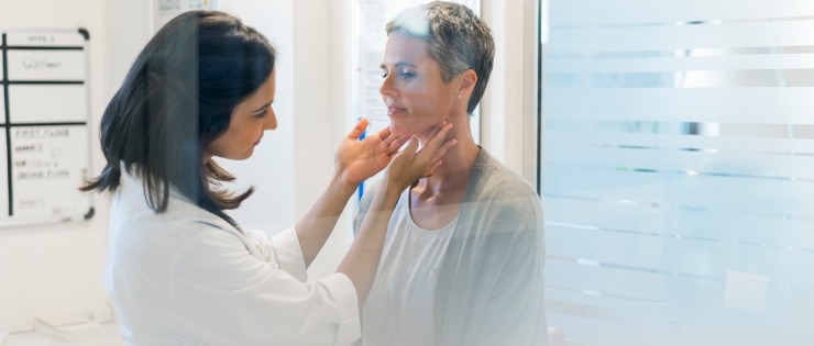 Doctor examining female patients thyroid