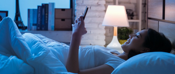 A woman playing on her phone before going to sleep