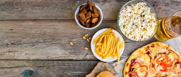Flat lay of salty foods that should be avoided before training such as hot chips, popcorn and pizza 