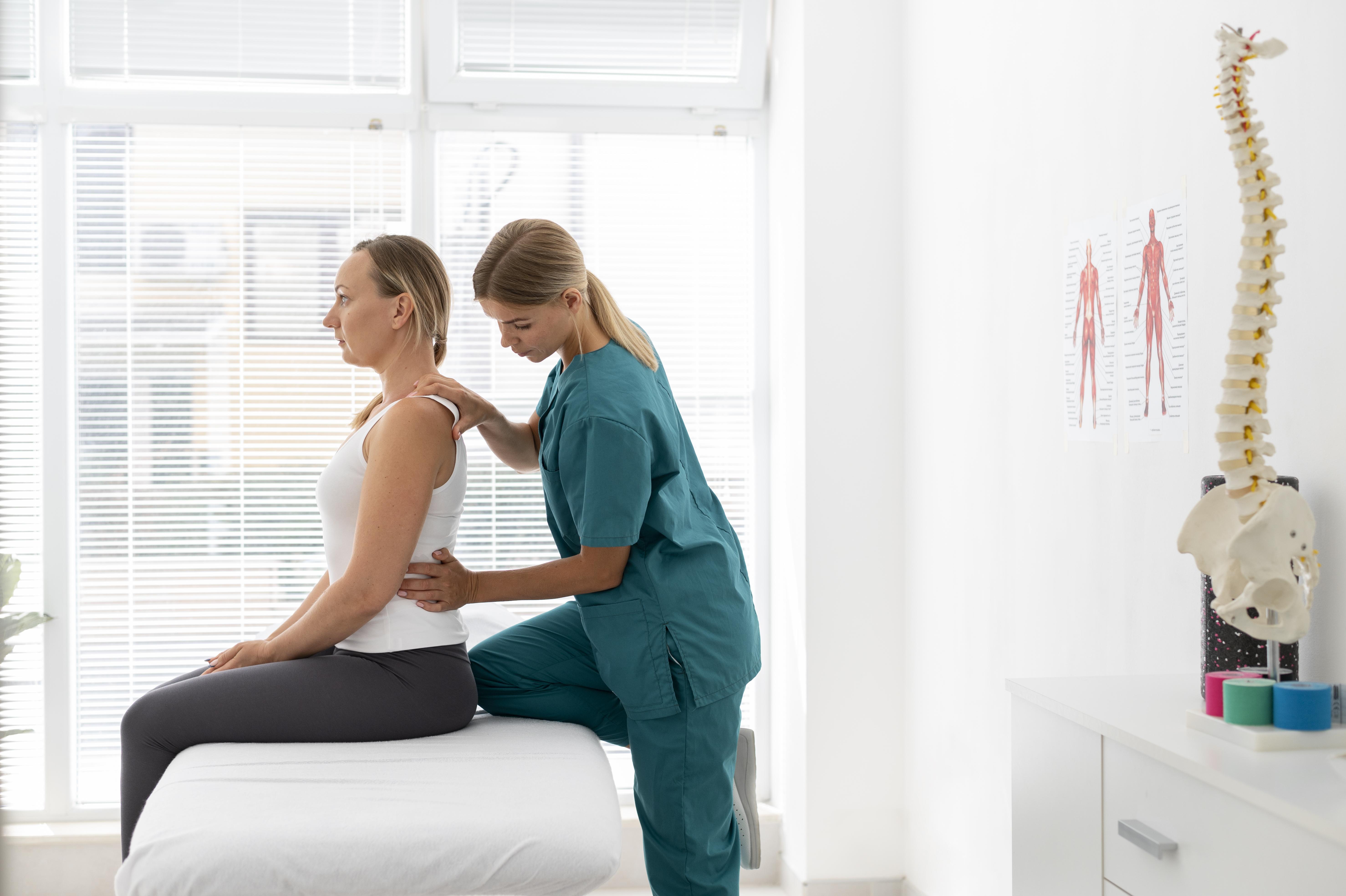 Lady sitting upright on adjustment table whilst physiotherapist applies pressure to problem areas on her back