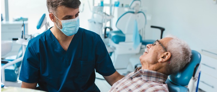 Elderly man discussing the cost of a root canal treatment with dentist 