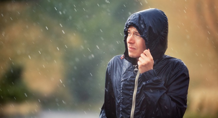 A man standing in the rain. Getting cold and wet does not cause a cold.