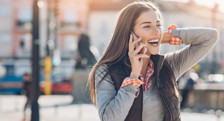 A smiling woman talking on the phone while away on holiday