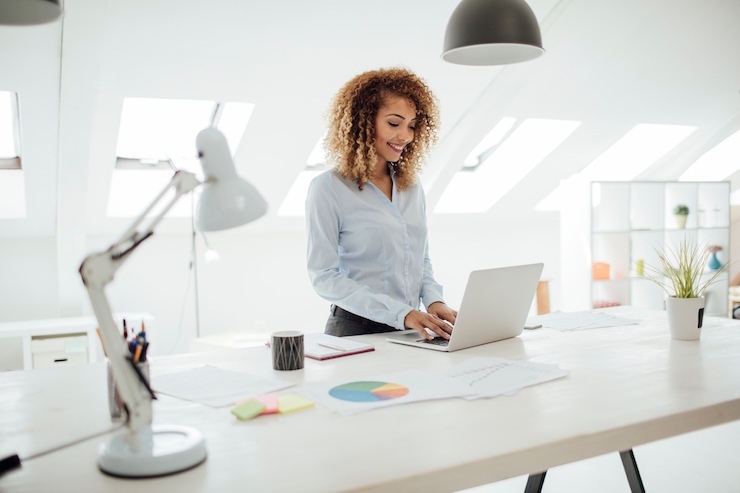 women standing at sit stand desk to keep healthy